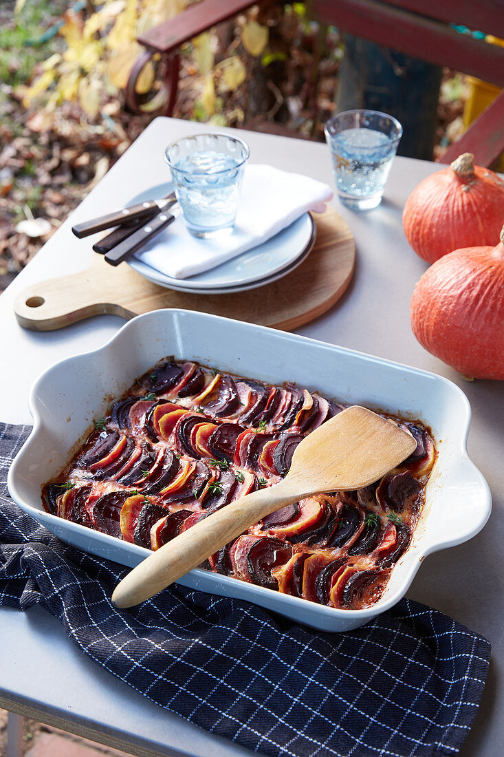 Gemüsegratin in Auflaufform auf Gartentisch