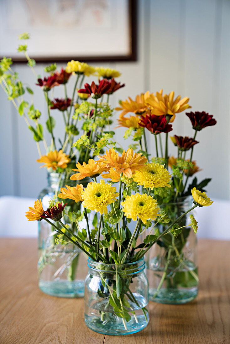 Blumen in Gelbtönen in Glasgefäßen