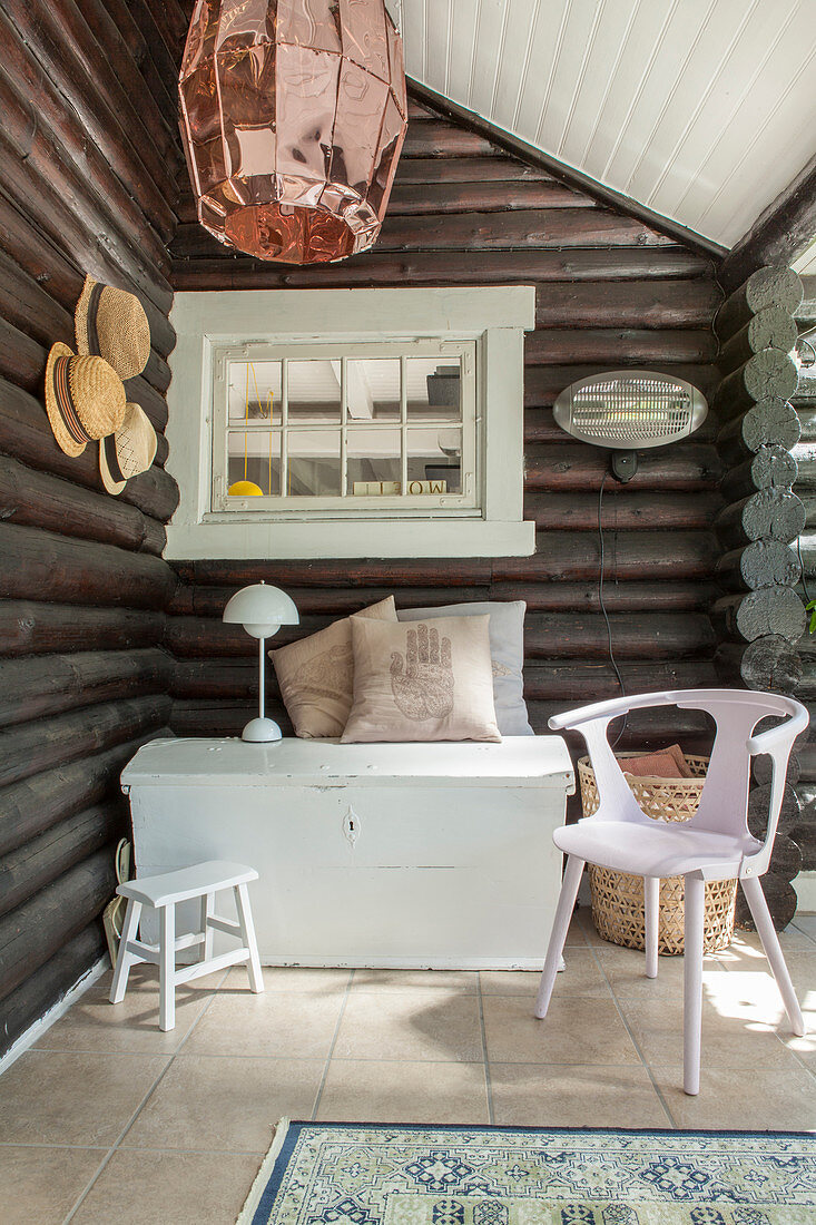 Trunk and chair on veranda of log cabin