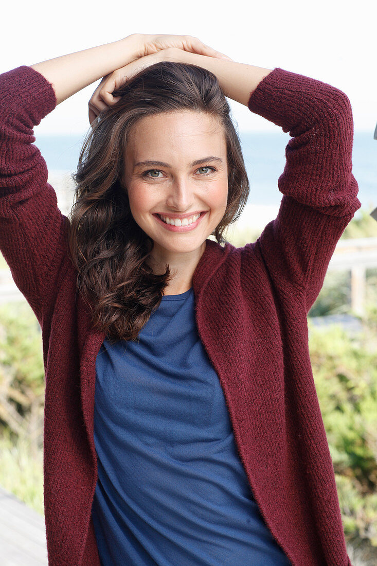 A young brunette woman wearing a blue t-shirt and a wine red cardigan