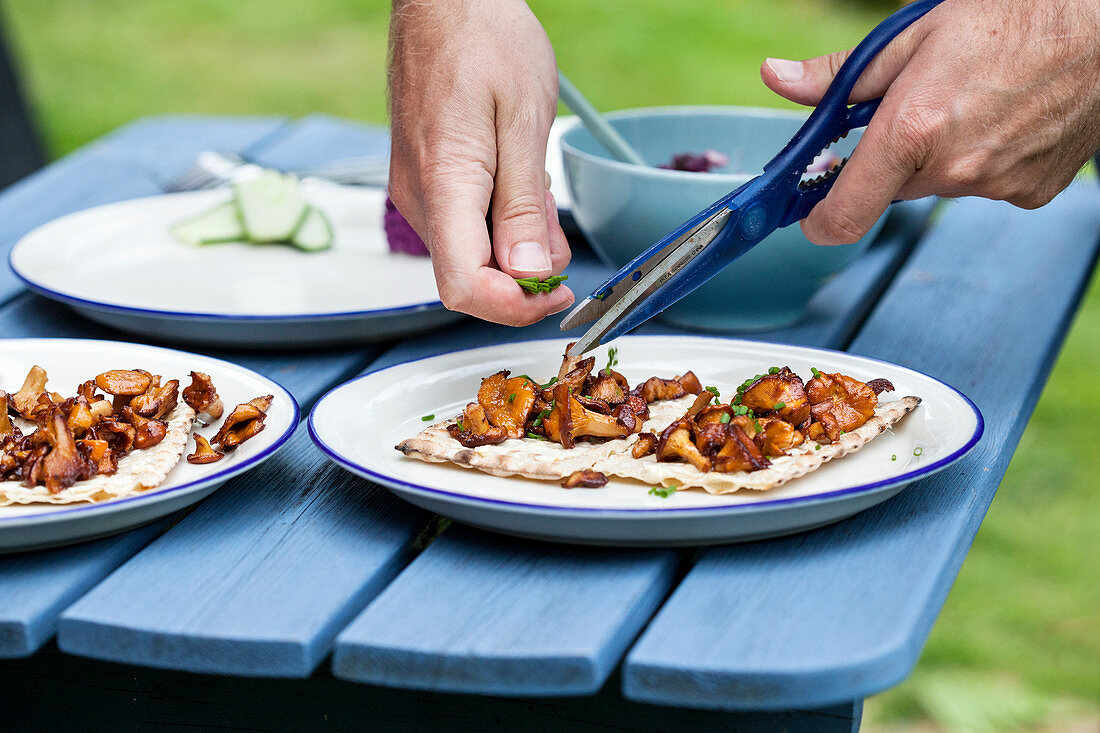 Close up of mans hands cutting herbs into dish