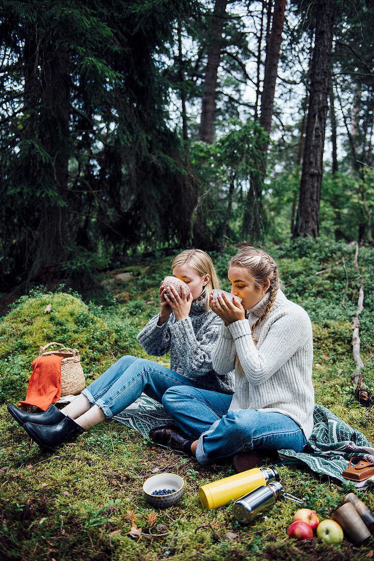 Zwei Frauen essen Suppe beim Picknick im Wald