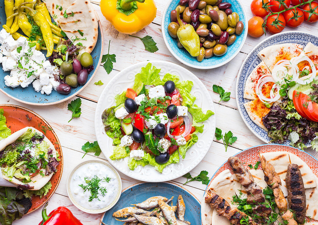 Greek food: Meze, gyros, souvlaki, fish, pita, greek salad, tzatziki, assortment of feta, olives and vegetables