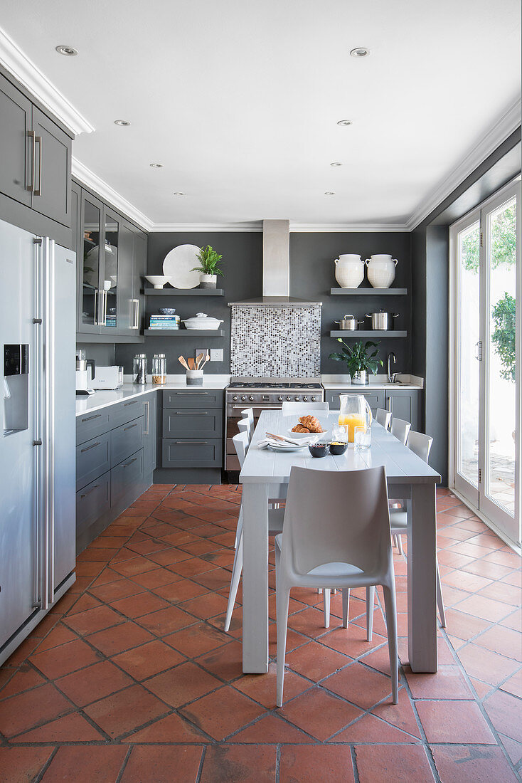 Log white table in kitchen-dining room with terracotta floor tiles