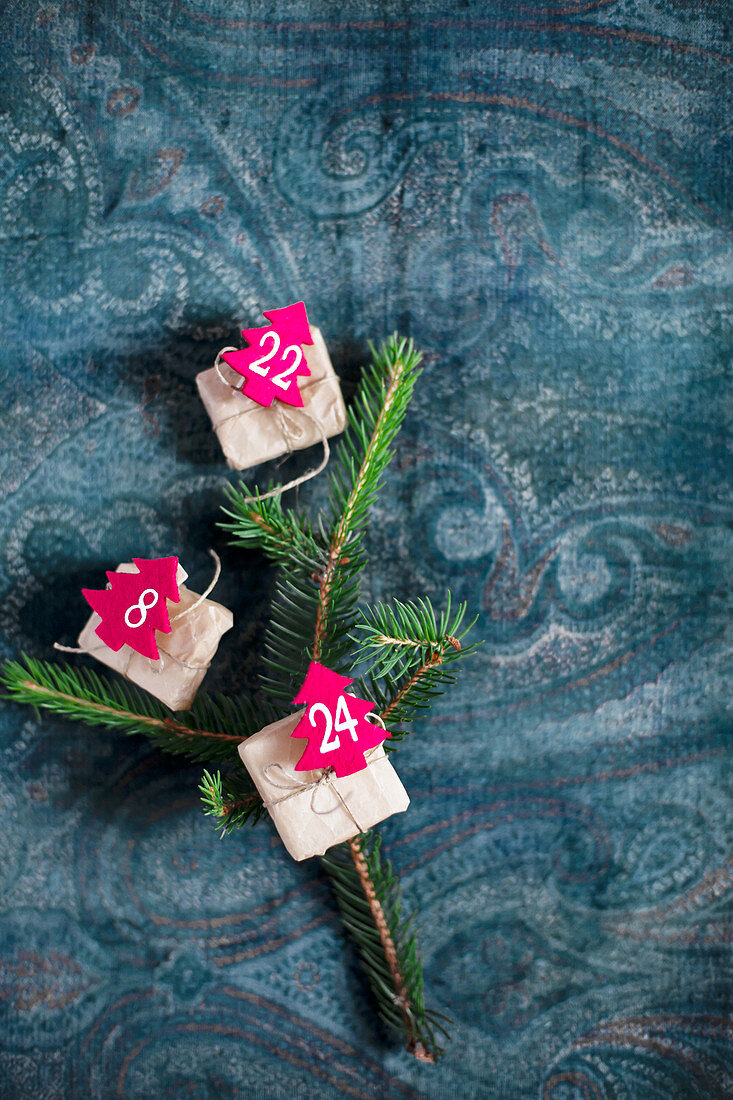 Geschenke mit nummerierten Filz-Bäumchen auf einem Fichtenzweig