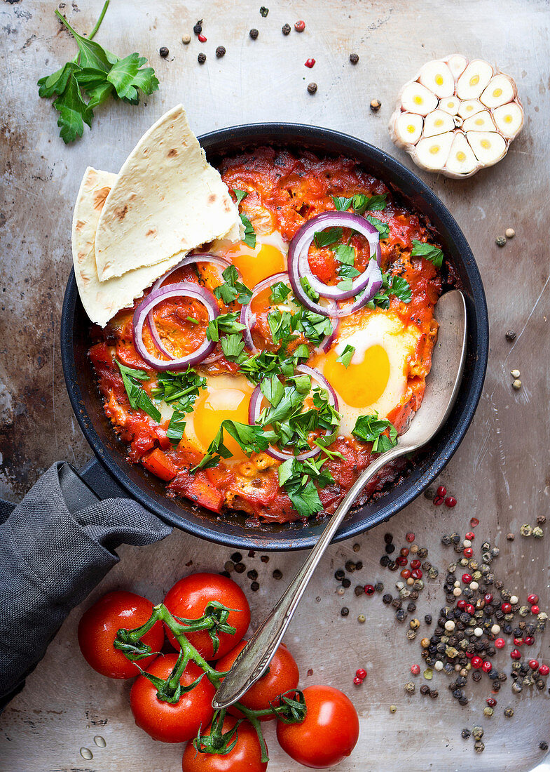 Shakshuka (Fried eggs with tomatoes, bell pepper, vegetables and herbs, Middle eastern traditional dish)