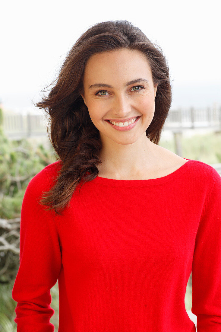 A young brunette woman wearing a red jumper