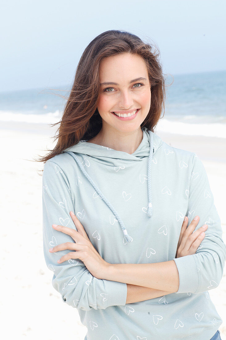 A young brunette woman wearing a light grey hooded top