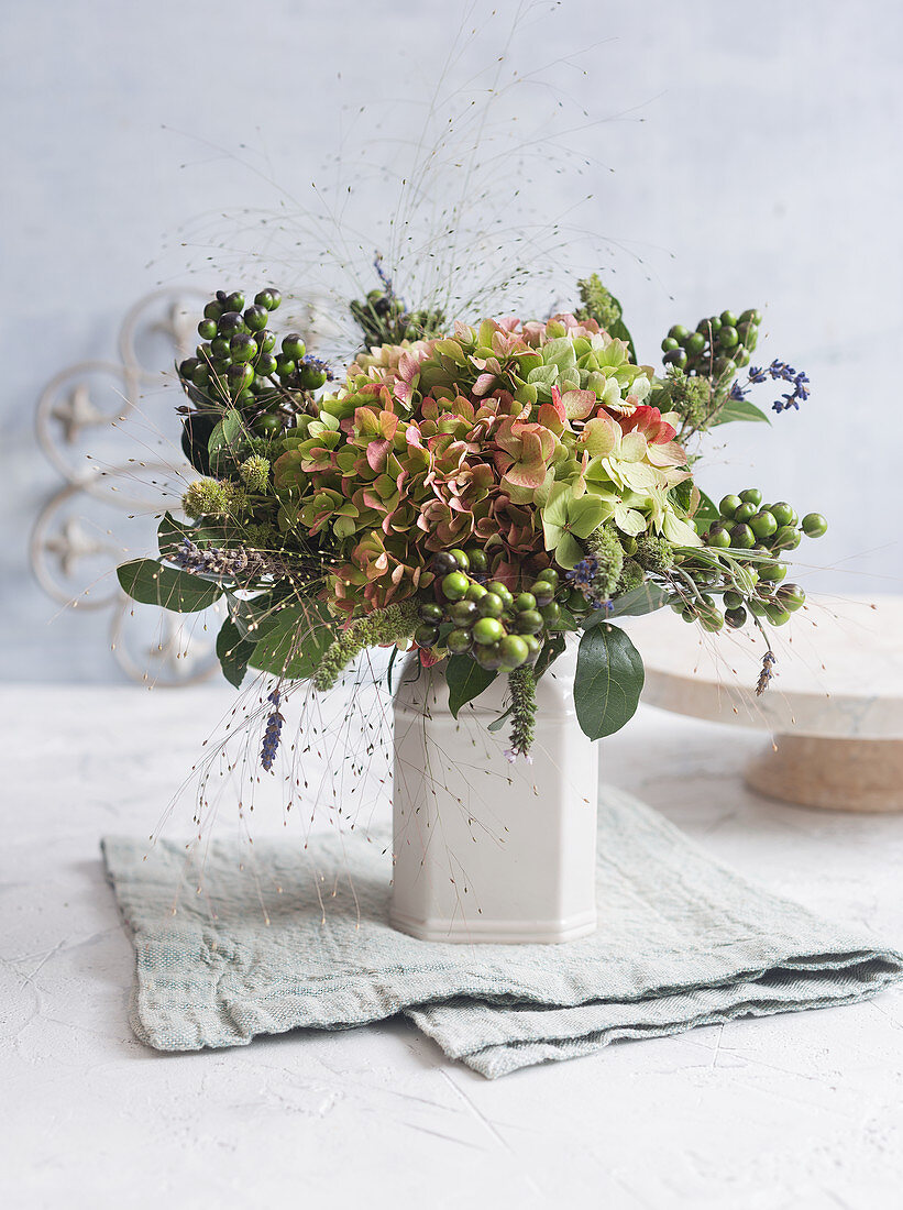 Herbstlicher Strauß mit Hortensienblüten, Hexengras und Büscheln von unreifen Oliven