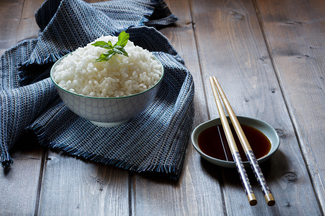 Boiled basmati rice in a bowl with chopsticks and soy sauce
