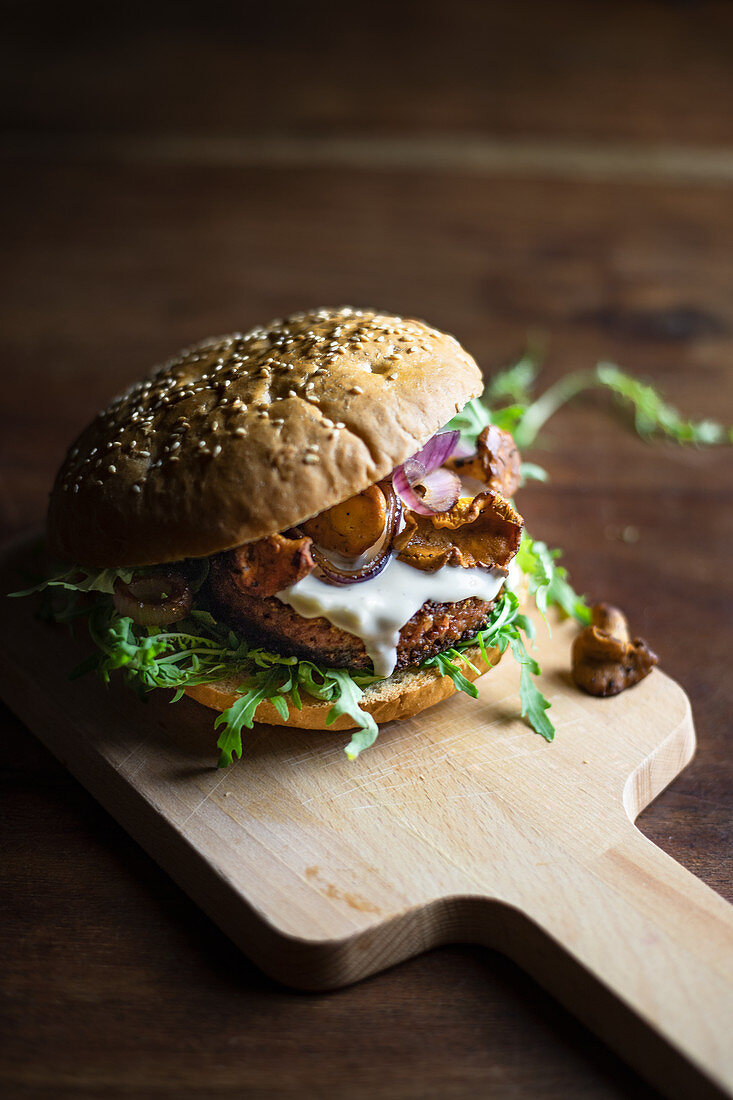 A burger with mushrooms and mayonnaise on a kitchen board