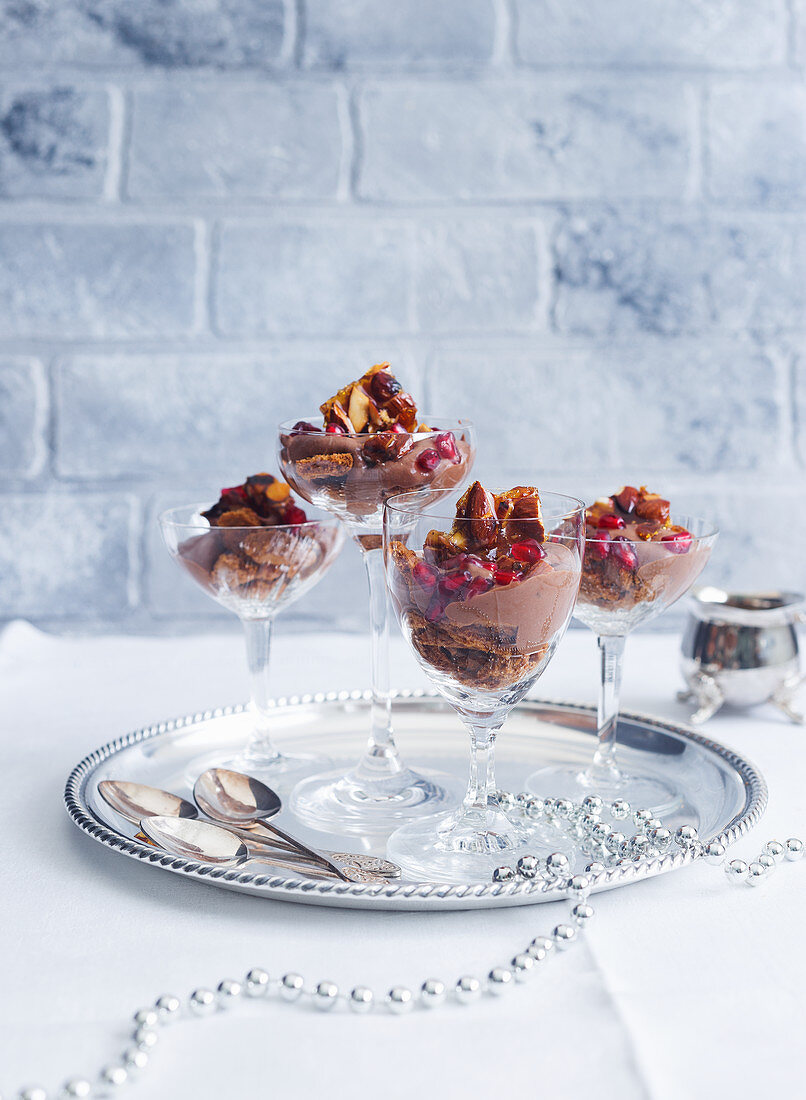 Glass desserts with biscuits, chocolate mousse, walnut britte and pomegranate seeds