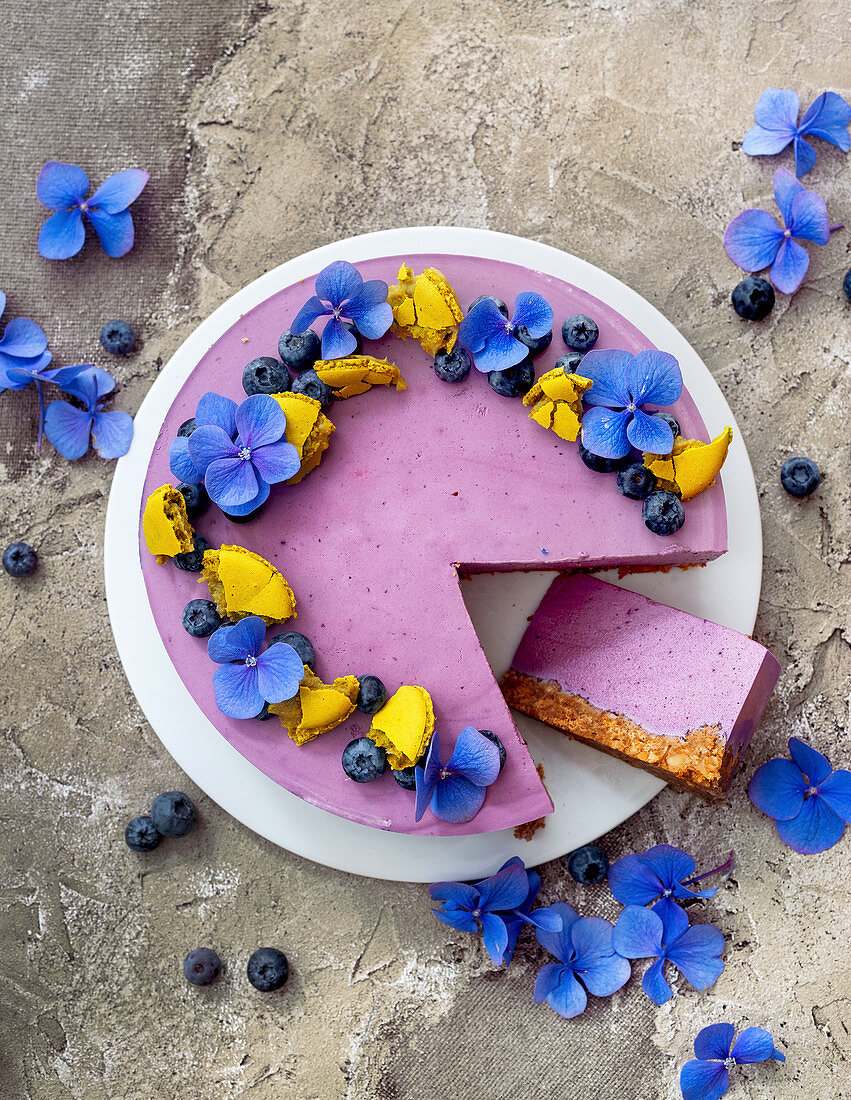 Heidelbeer-Frischkäse-Torte, dekoriert mit Macarons und Blüten