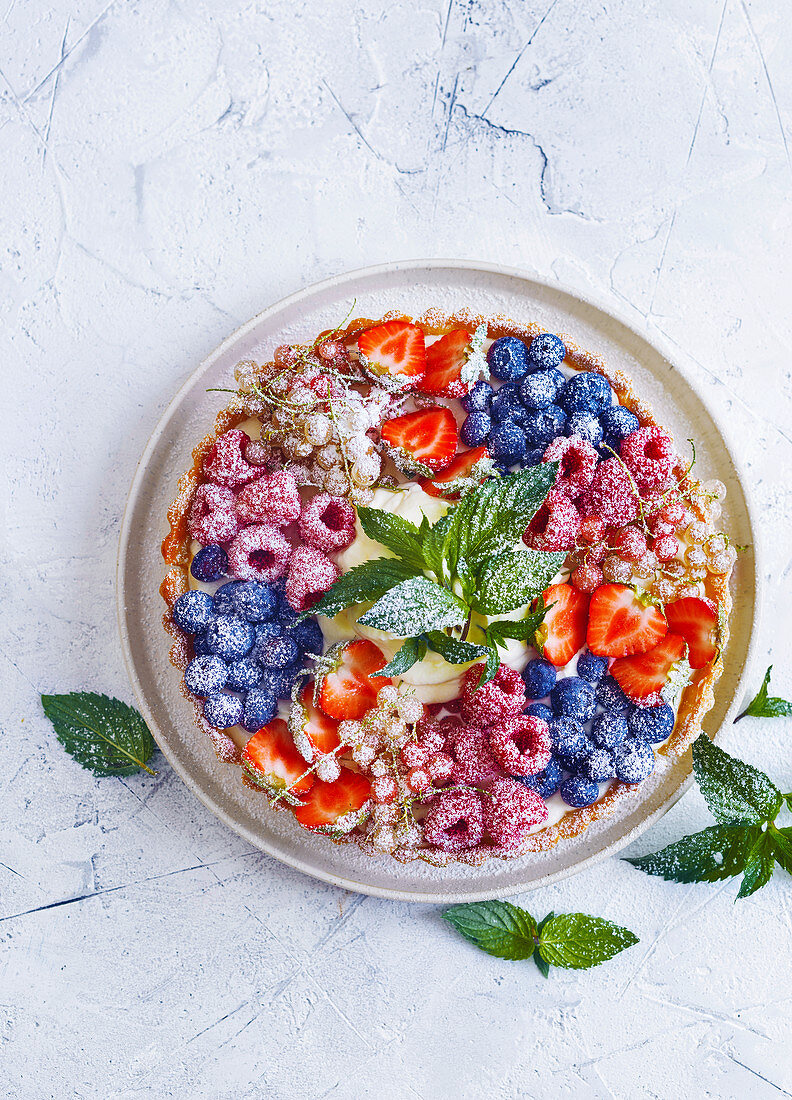 Berry tart with powdered sugar and fresh mint