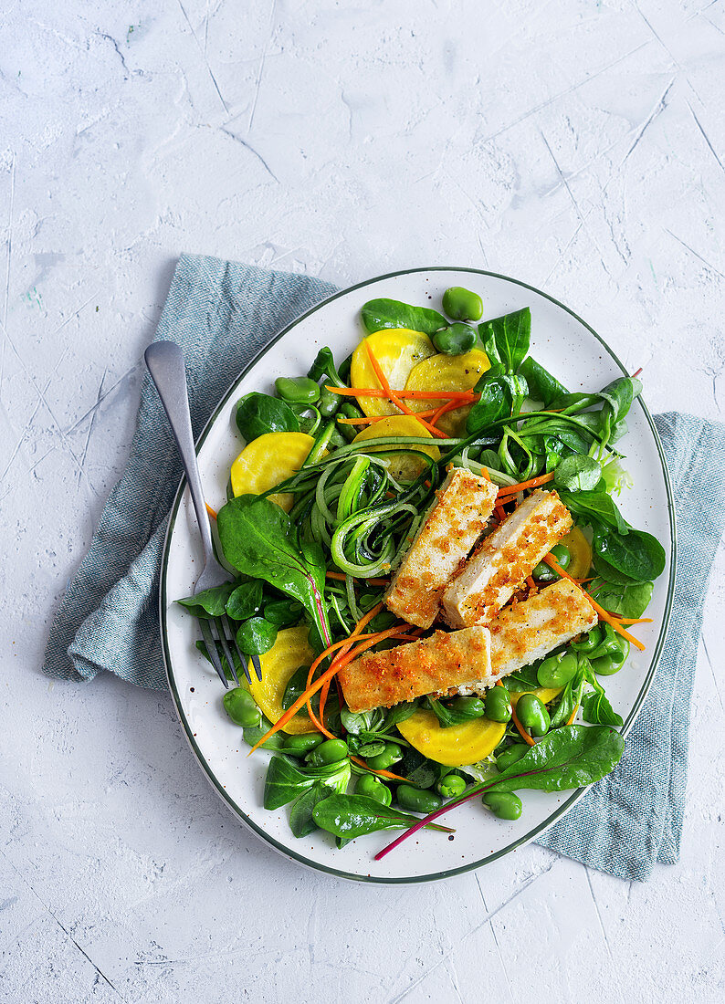 Vegan salad with yellow beet, zucchini, beans and breaded tofu