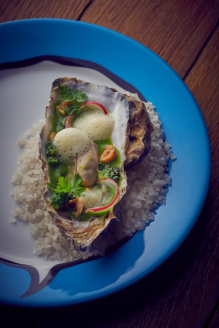 Oyster with foam sauce on a salt bed