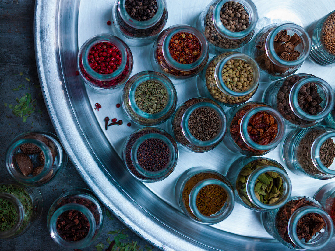 Various spices in glass jars on a tray