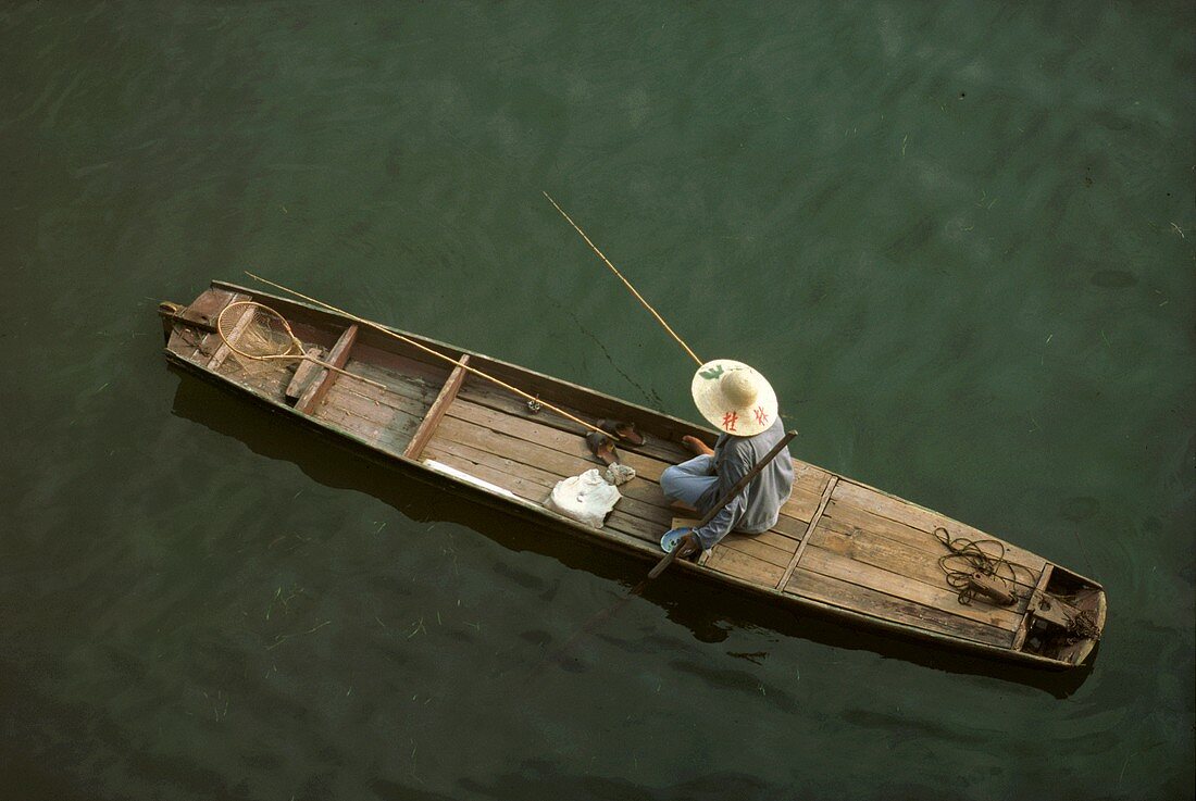 Person Fishing in Boat on Chinese River