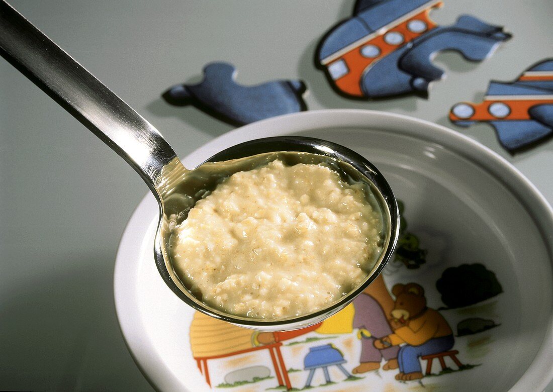 Porridge (Haferbrei) auf Kelle über Kinderteller