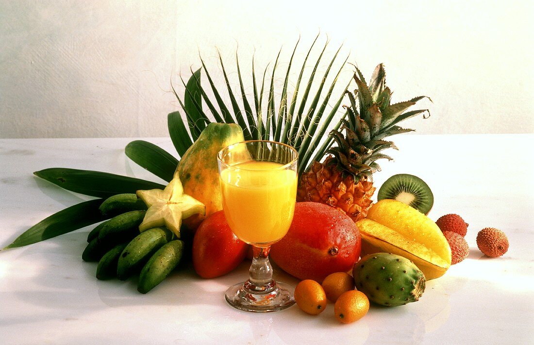 A glass of orange juice and a few fresh exotic fruits