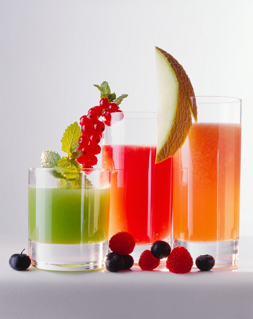 Three different fruit juices in glasses, fruit & berries