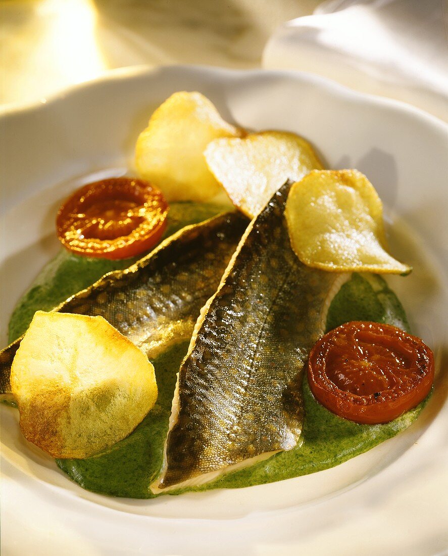 Brook trout fillet on green sauce with potato crisps & tomatoes