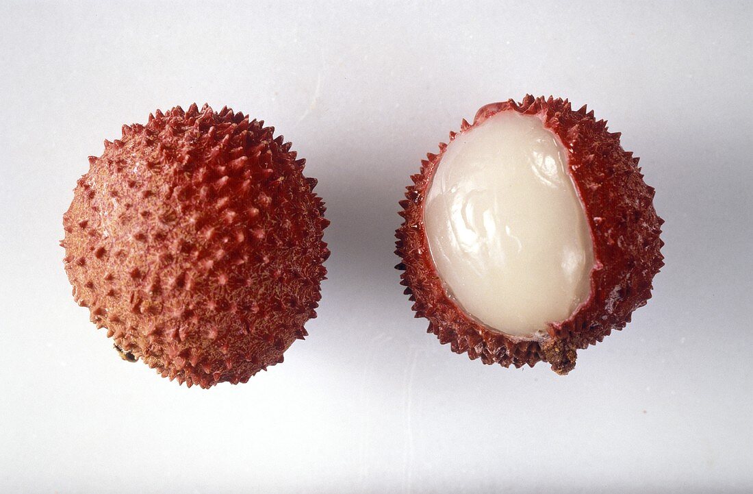 Two lychees, one whole and one half-peeled