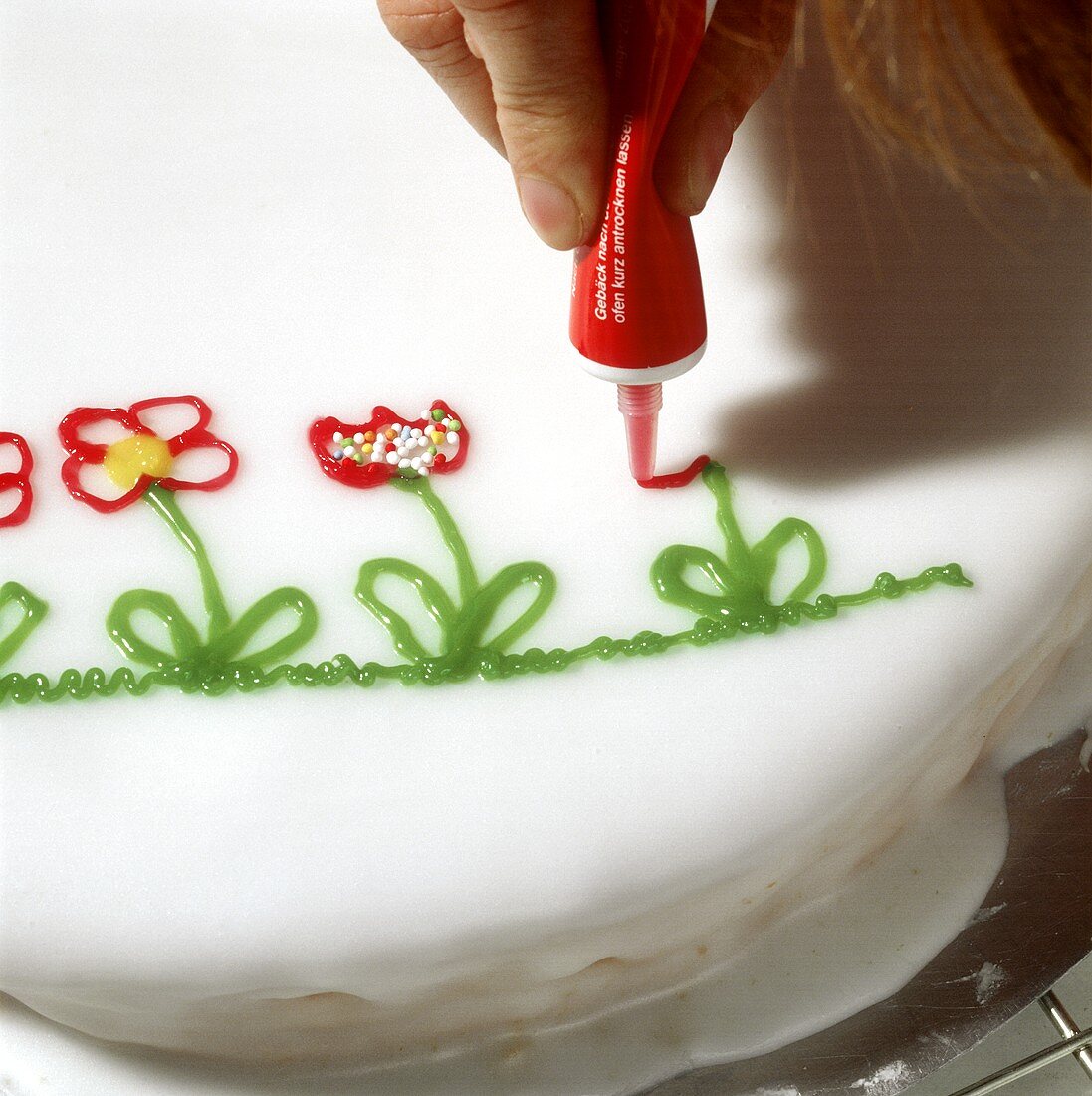 Decorating a cake with flowers (icing from a tube)