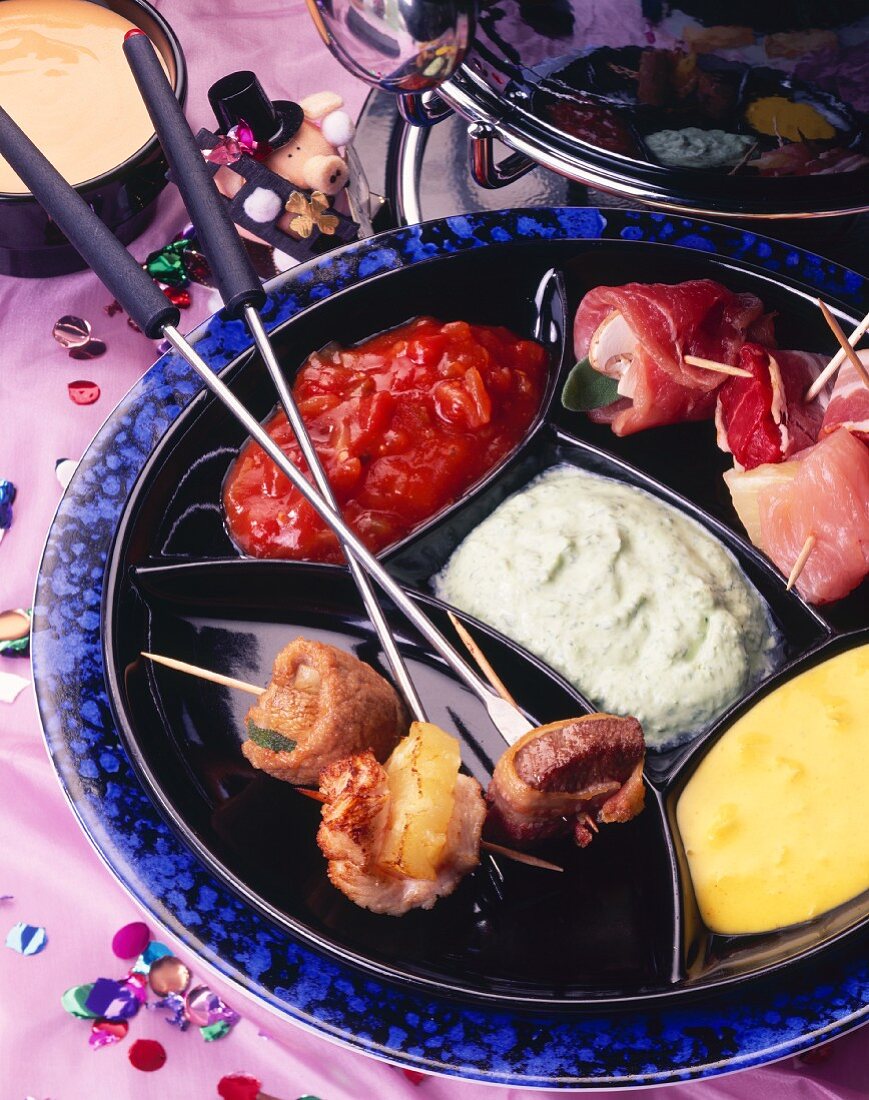 New Year's Eve fondue with stuffed skewered meat & sauces