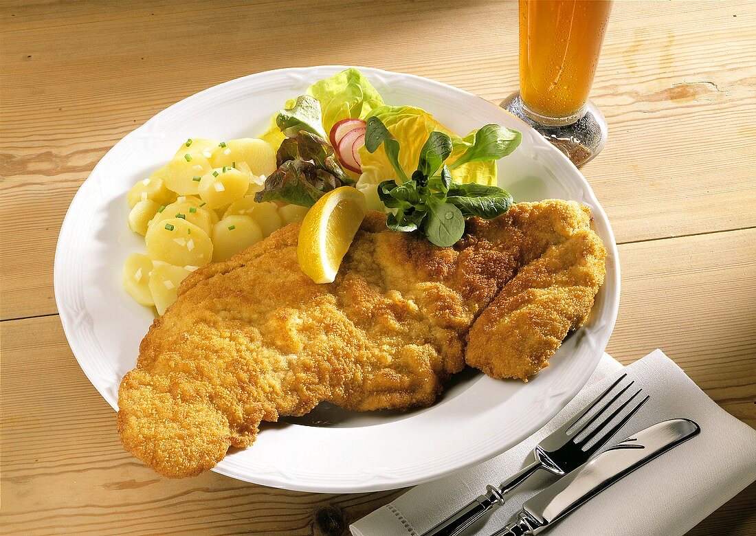 Wiener Schnitzel with salad and potatoes on plate