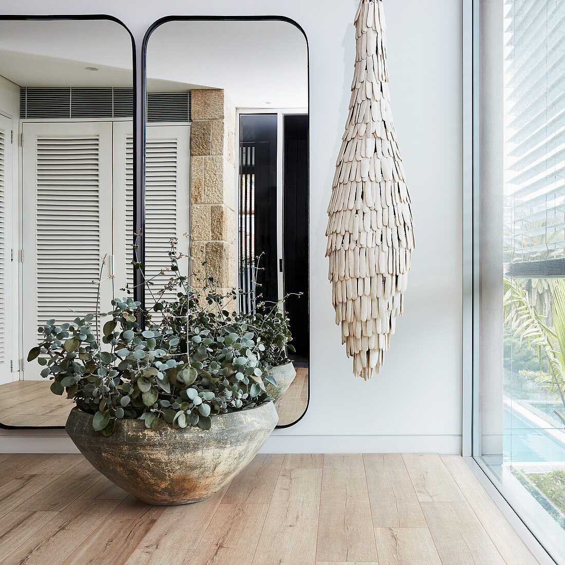 Potted sedum and suspended artwork next to wall-mounted mirrors