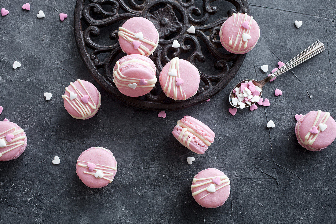 Basic macarons colored in pink and decorated with white chocolate and hearts