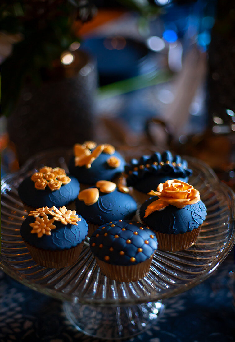 Perfectly decorated cupcakes with dark blue and gold toppings
