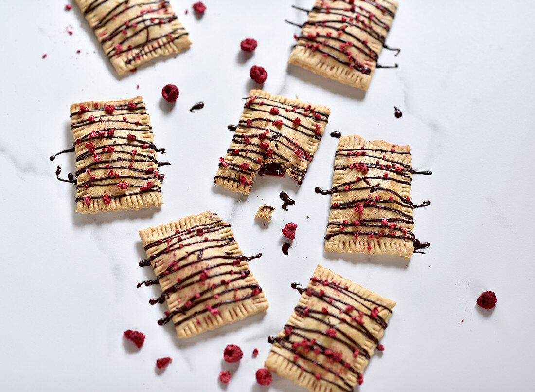 Vegan pop tarts filled with jam and topped with chocolate and dried raspberries