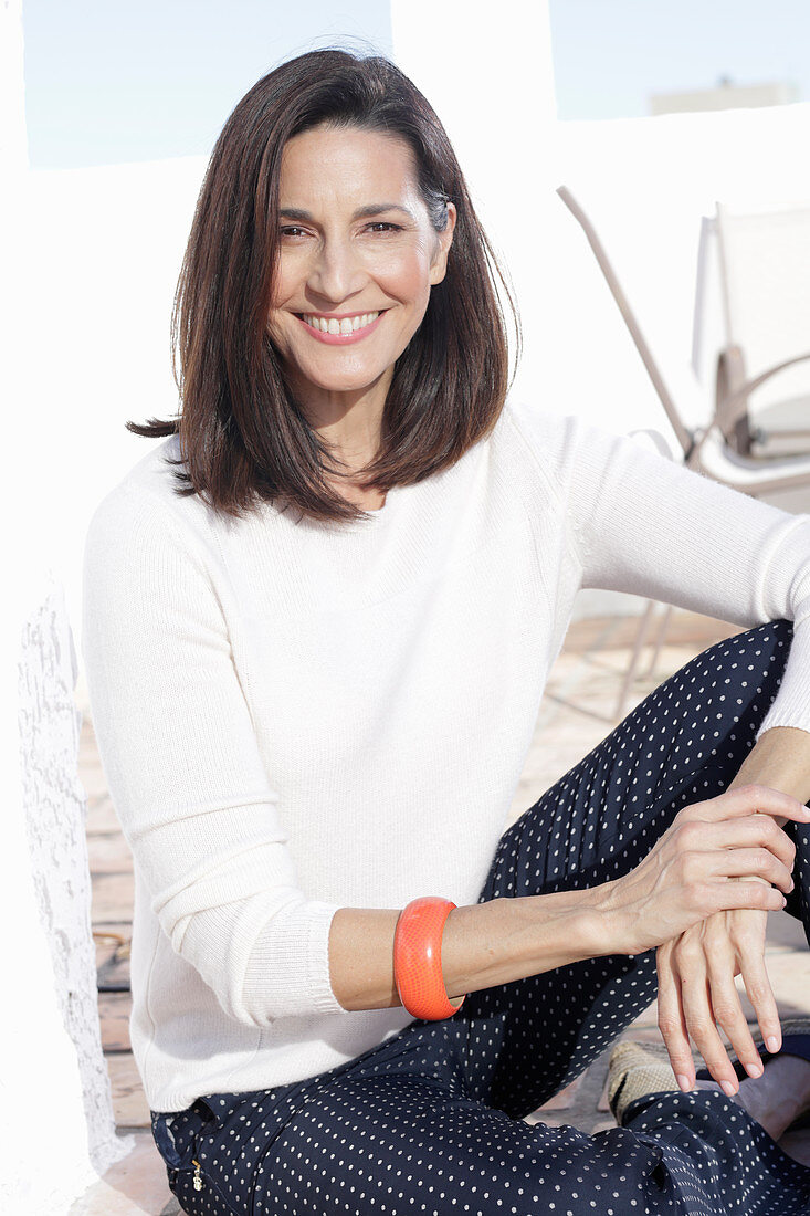 A brunette woman wearing a white jumper and polka dot trousers