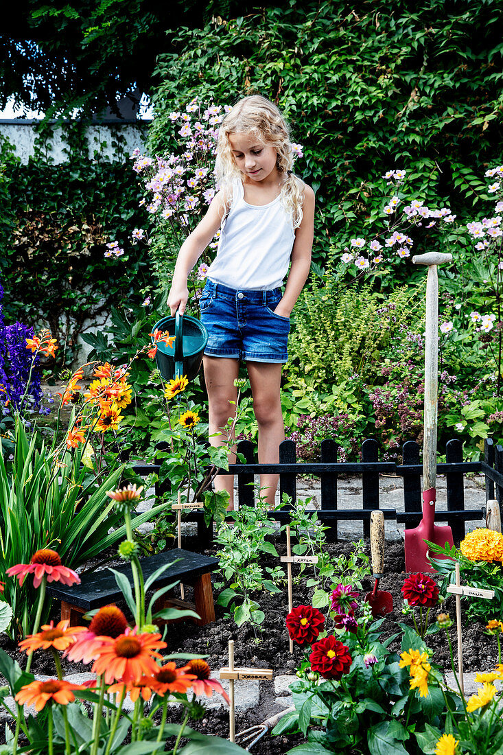Girl watering flowers in the fenced mini-garden