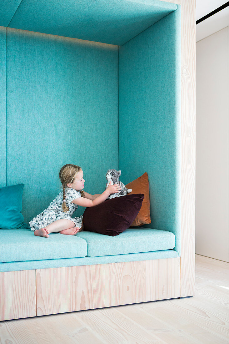 Girl playing in seating niche upholstered in pale blue
