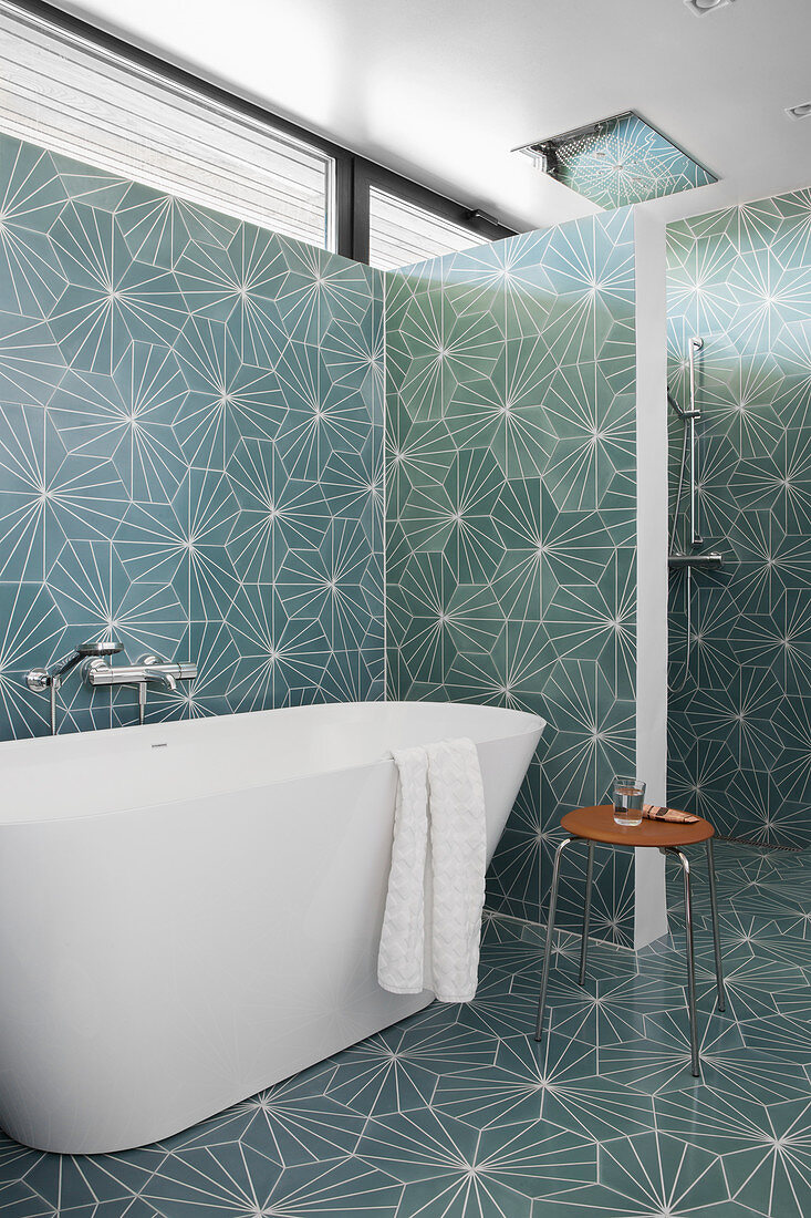 Free-standing bathtub in bathroom with patterned tiles on walls and floor