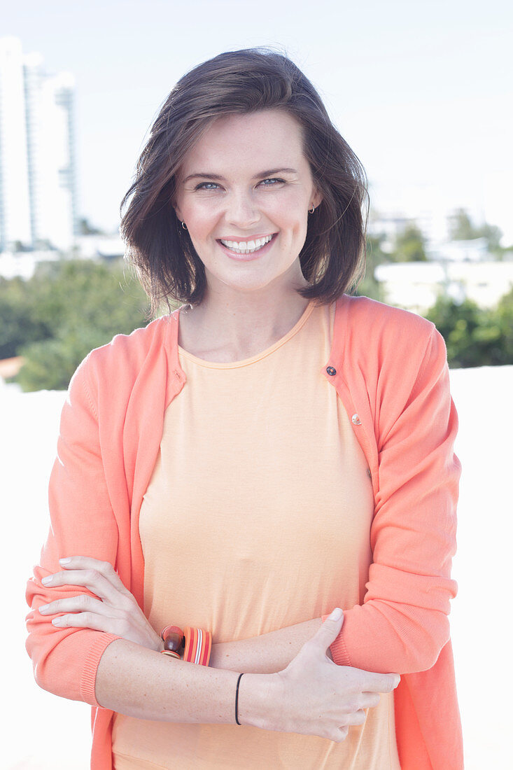 A young woman wearing an apricot top and cardigan