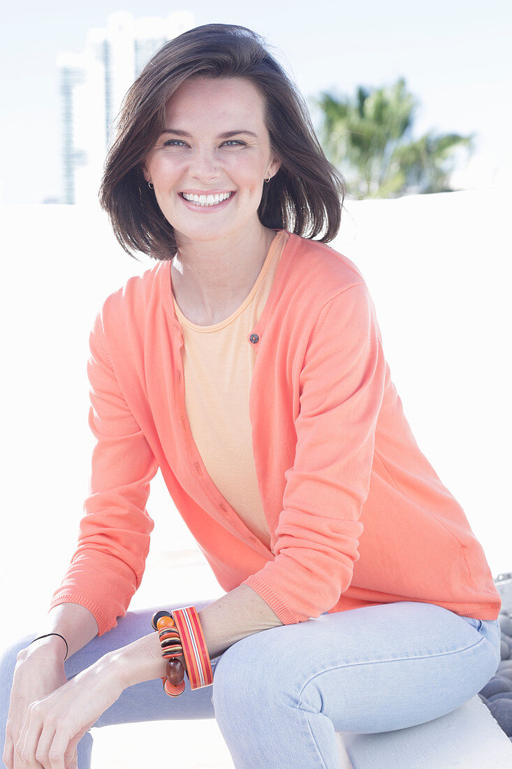 A young woman wearing an apricot top, cardigan and jeans