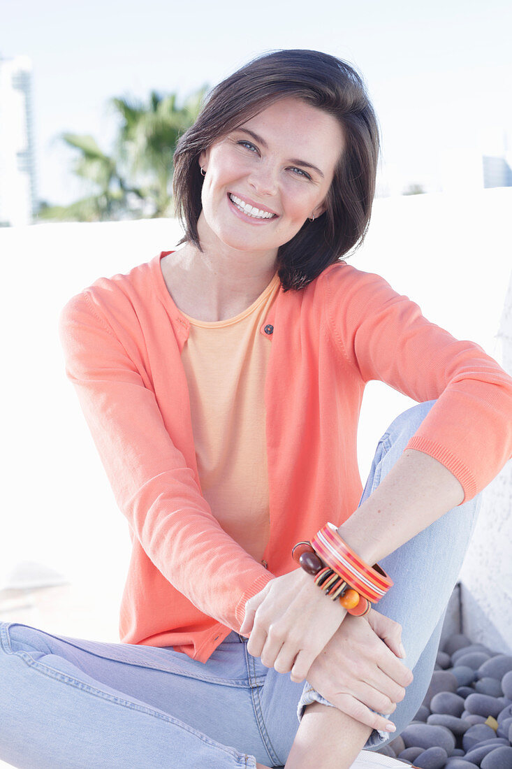 A young woman wearing an apricot top, cardigan and jeans