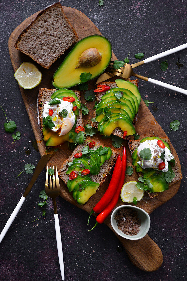 Toasts with avocado and poached egg on a wooden board