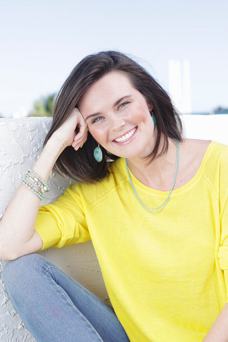 A young woman wearing a long-sleeved yellow top and jeans