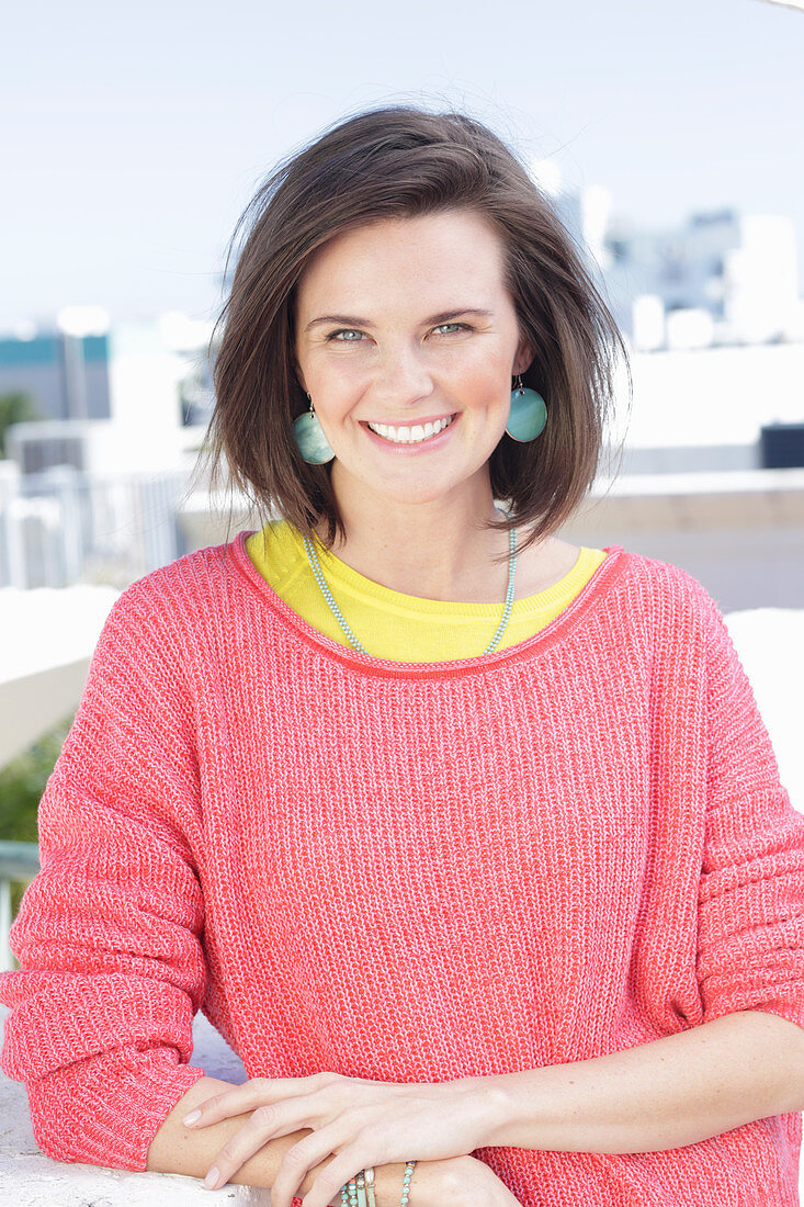 A young woman wearing large earrings, a fuchsia jumper and a yellow top