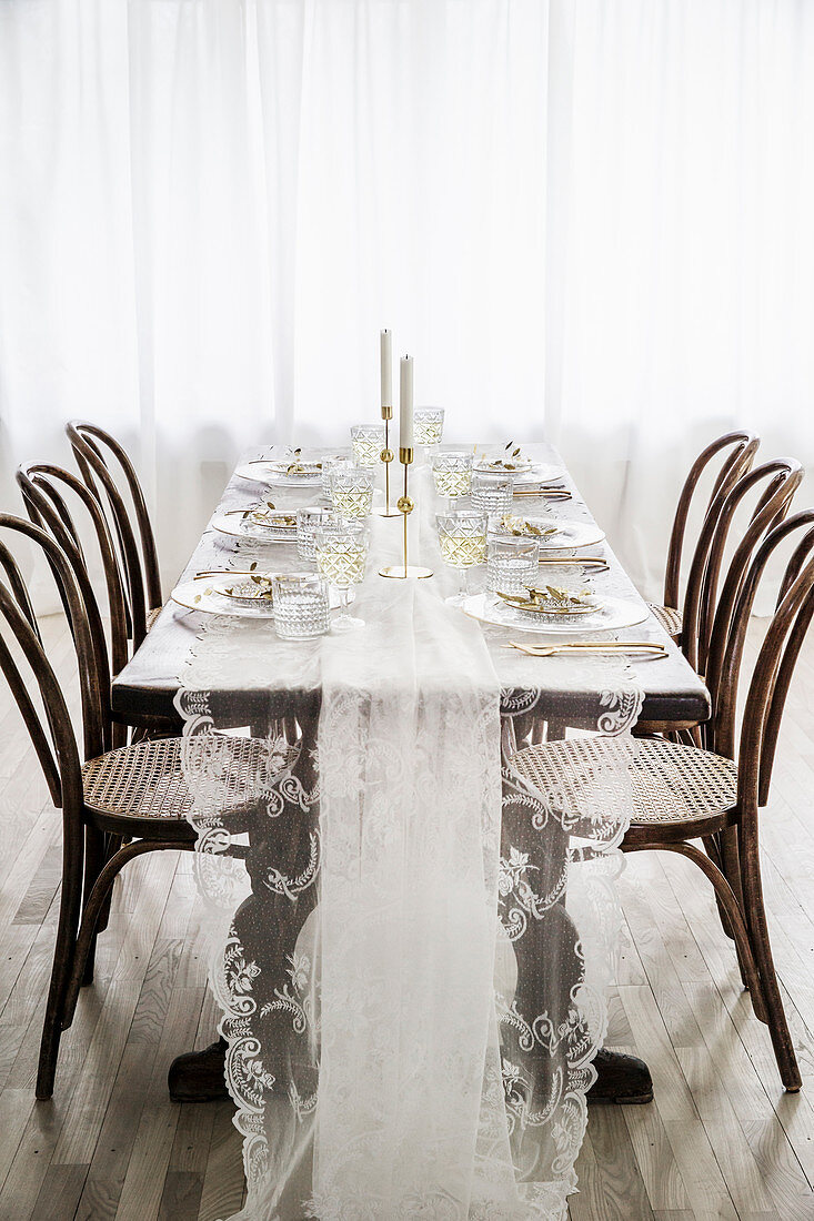 Bistrostühle am gedeckten Tisch mit Tischdecke aus Spitze