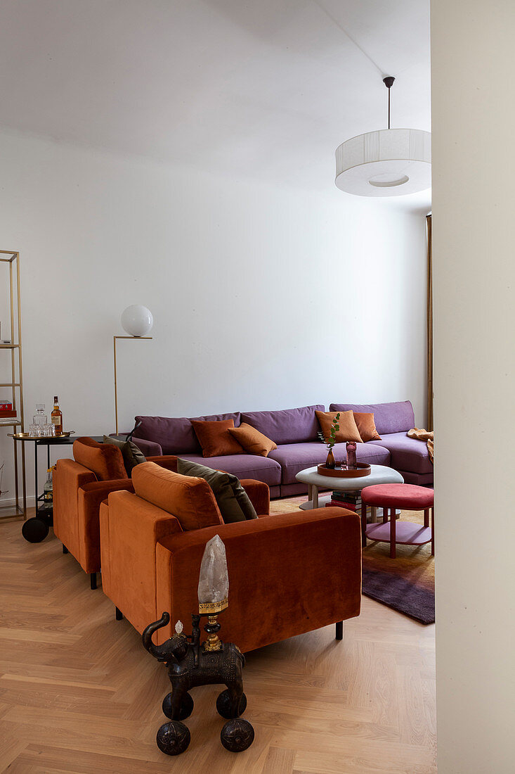 Orangefarbene Sessel und pinkes Sofa im Wohnzimmer