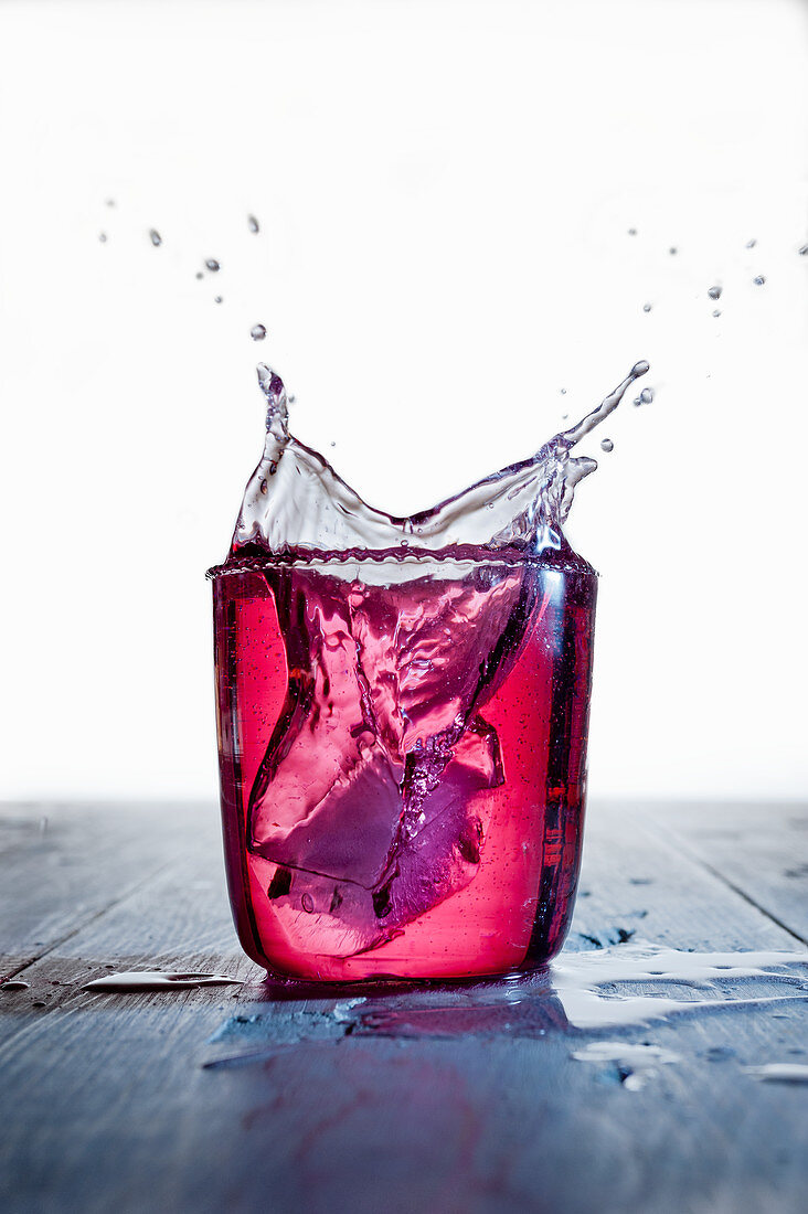 A red drink splashing against a white background