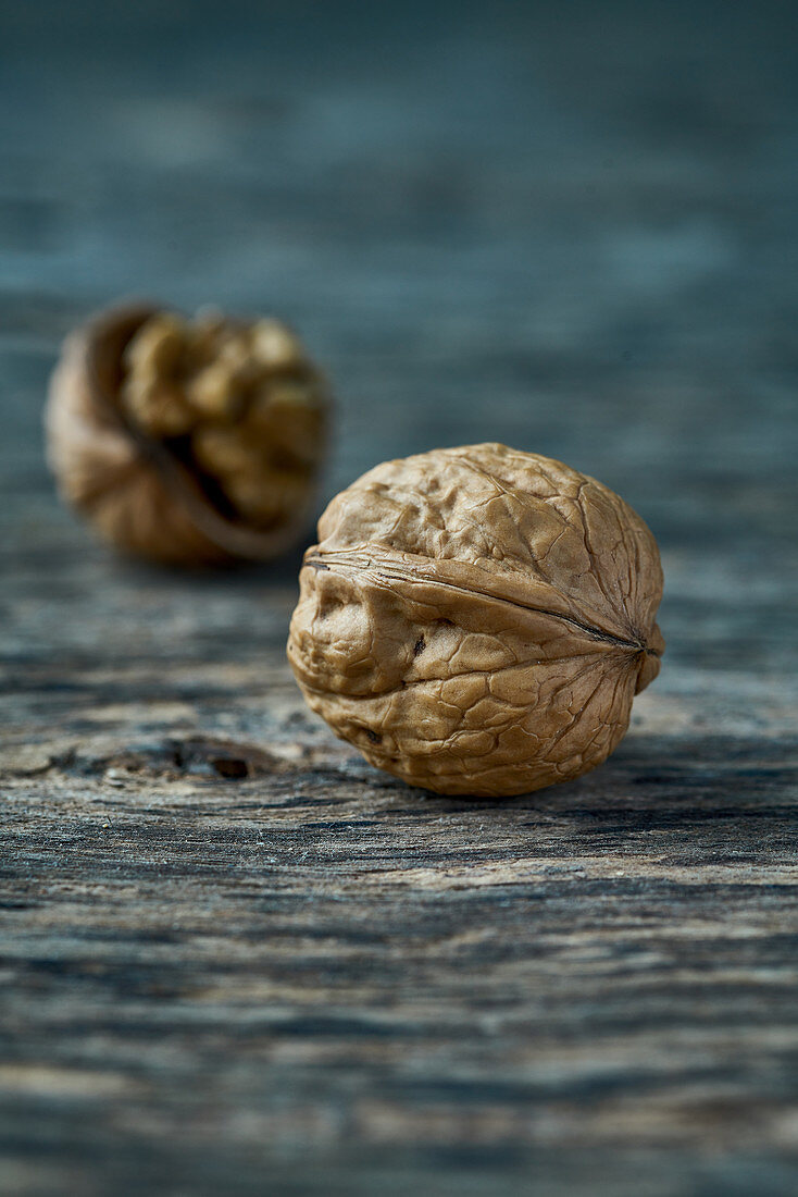 A whole and an open walnut on a wooden surface