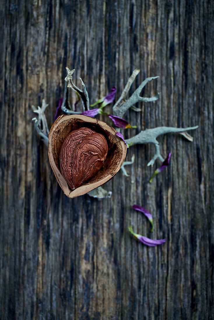 A half-shelled hazelnut on a wooden surface