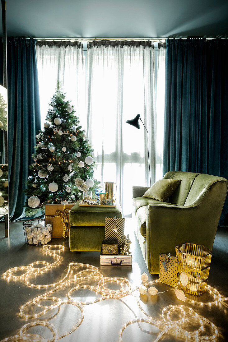 Green living room festively decorated with fairy lights and Christmas tree